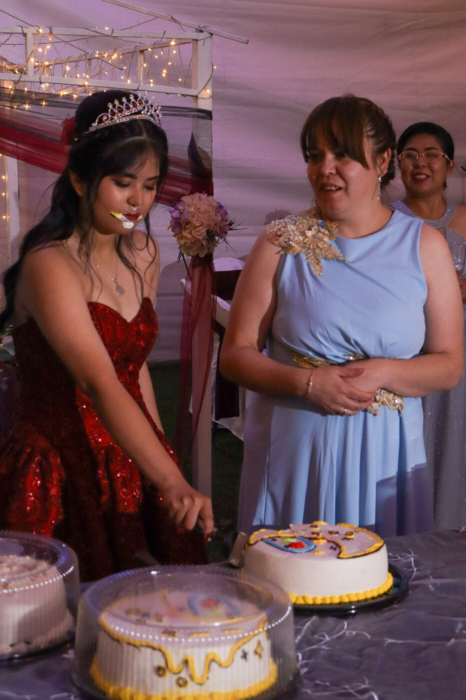 Quinceañera partiendo el pastel con su mamá