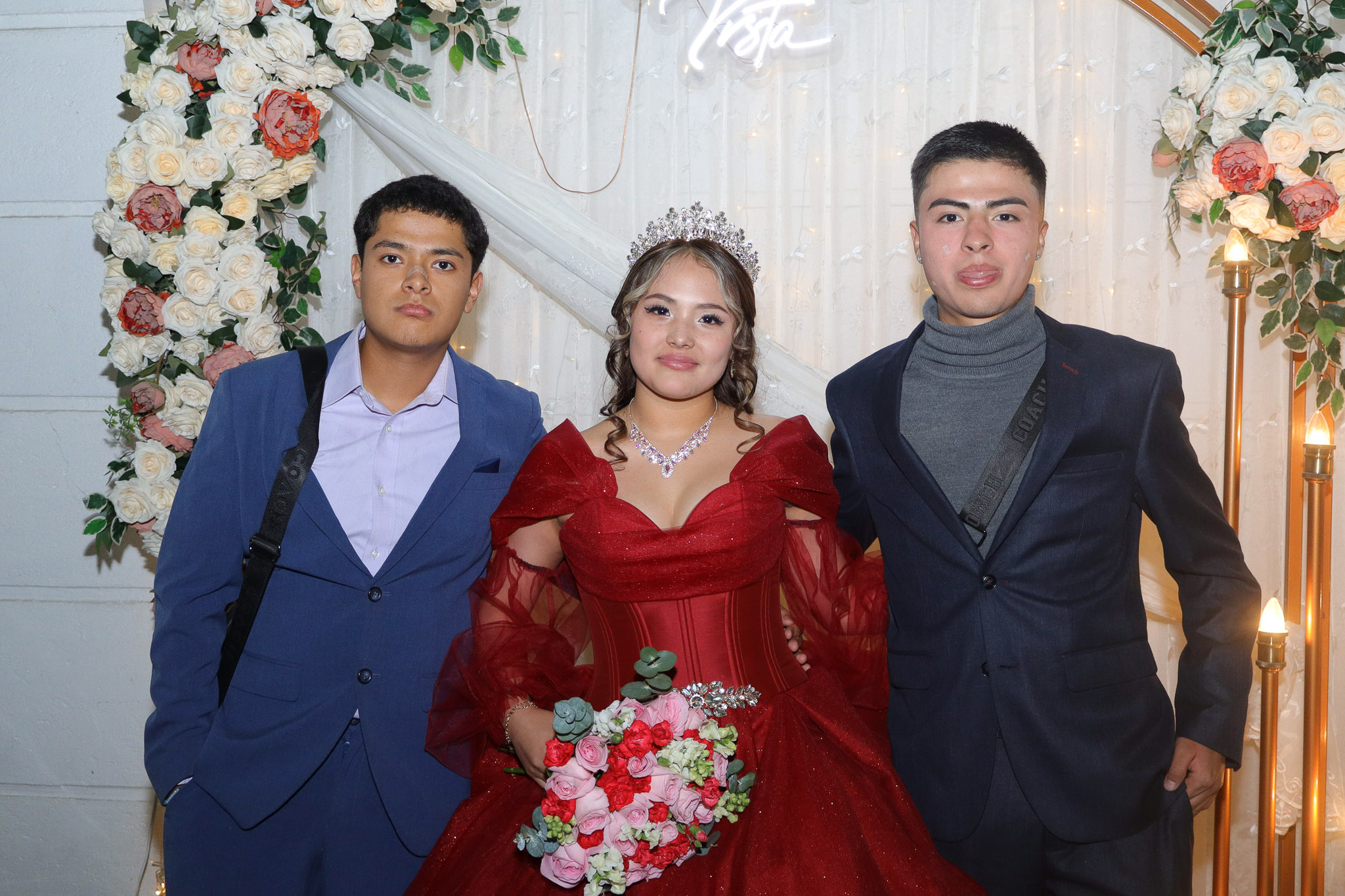Quinceañera con sus invitados frente al arco floral