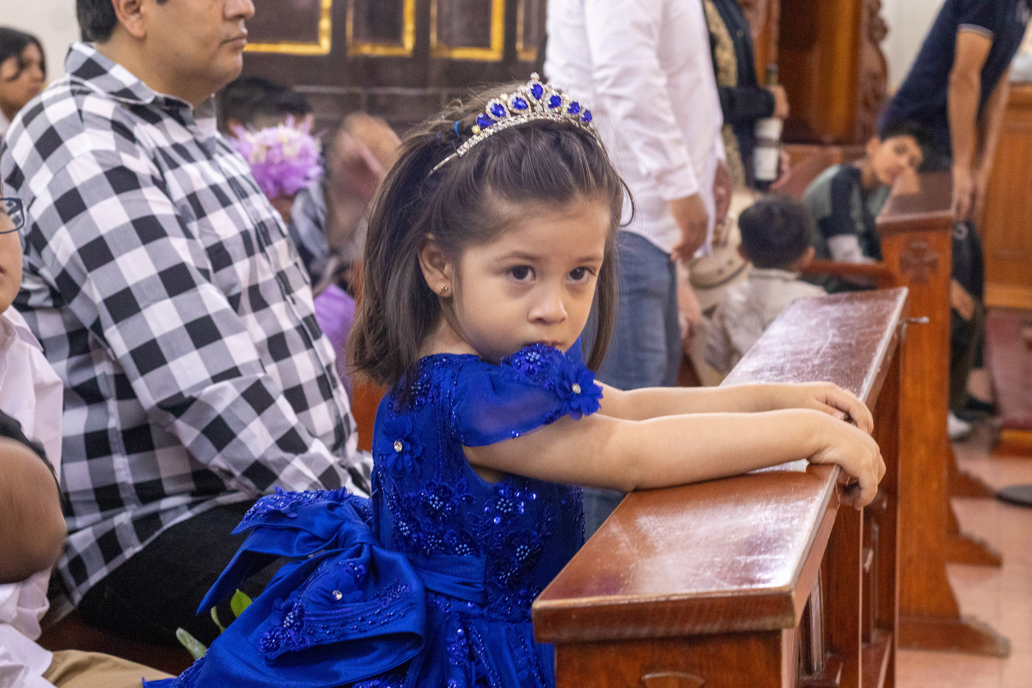 Niña con corona y vestido azul durante la misa