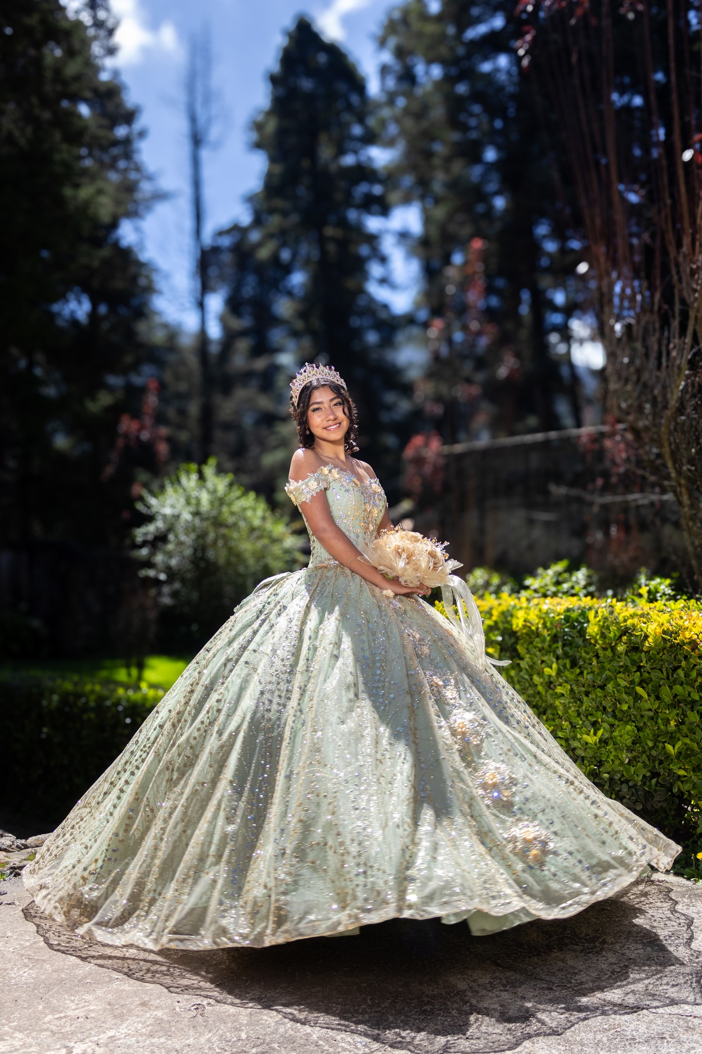 Quinceañera en jardín con vestido verde